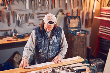 Male carpenter working on old wood in a retro vintage workshop.