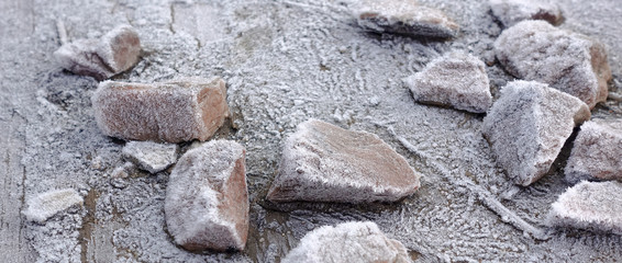 Stones on a wooden base covered with hoarfrost. Winter frosty background.