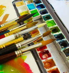 Set of watercolor paints and paintbrushes for painting closeup. Selective focus.