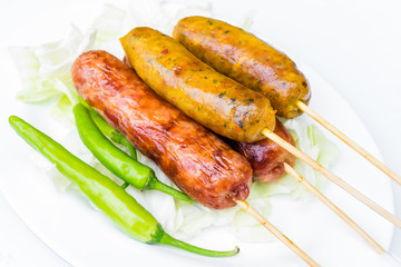 Pork sausage in a white dish with green peppers.
