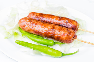 Pork sausage in a white dish with green peppers.