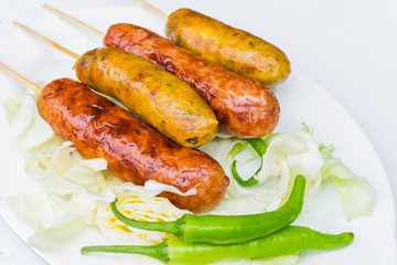 Pork sausage in a white dish with green peppers.