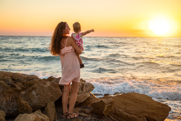 Fototapeta na wymiar Mother and baby having fun at sunset beach