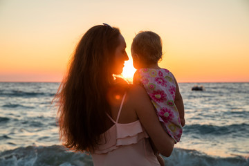 Mother and baby having fun at sunset beach