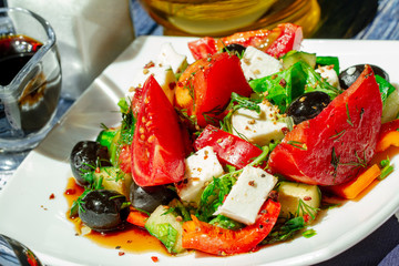 Traditional greek salad with fresh vegetables, feta cheese and olives. Selective focus. salad of cucumber, tomato, sweet pepper, lettuce, feta cheese, olives with olive oil and sea salt. Rustic style.