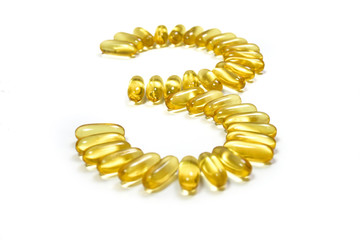 Close up of gold fish oil capsules in cup isolated on white background. Omega 3 with Vitamin E. Supplementary food background view. Salmon fish capsules. Number 3.
