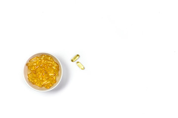 Top view of Gold fish oil capsules isolated in white bowl on white background. Omega 3. Vitamin E. Supplementary food background. Salmon fish capsules view.