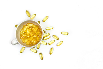 Top view of gold fish oil capsules in cup coffee isolated on white background. Omega 3 with Vitamin E. Supplementary food background view. Salmon fish capsules with Copy space.