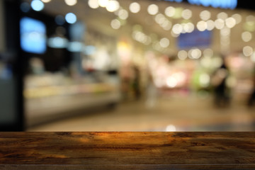 Fototapeta premium Empty dark wooden table in front of abstract blurred bokeh background of restaurant . can be used for display or montage your products.Mock up for space.