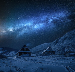 Small cottages in winter mountains and milky way