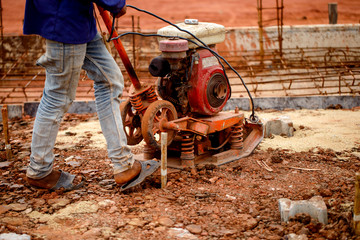 Construction worker is using compacted soil compactor.