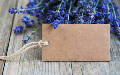 Empty tag and lavender flowers on a old wooden table © Olena Rudo