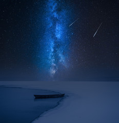 Milky way and alone boat on frozen lake in winter