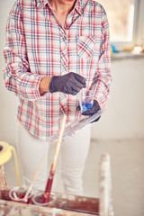 Fototapeta na wymiar Working woman plastering / painting walls inside the house.