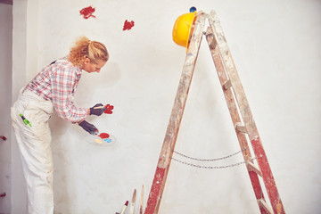 Working woman plastering / painting walls inside the house.