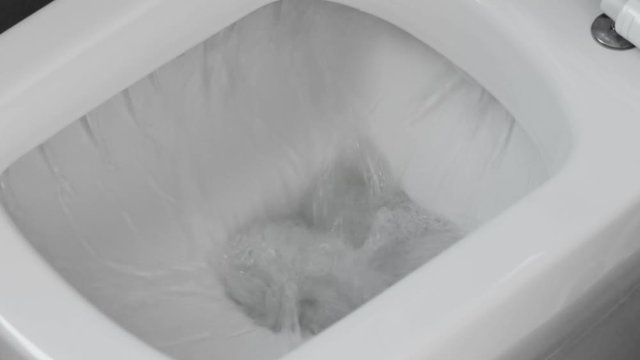 White toilet bowl in a bathroom. Closeup. Flush water away