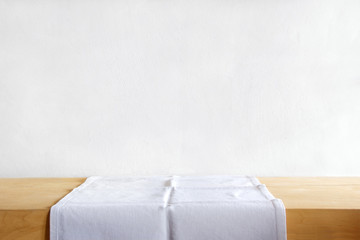 Rustic table with a white table linen against grunge cement wall. Vintage background template,...