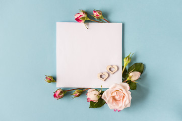 Flowers composition with hearts. Postcard concept. Greeting card made of pink rose flowers on blue background. Flat lay, top view, copy space, soft focus. Minimalism.