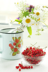 A bouquet of wildflowers and a glass bowl of red currant
