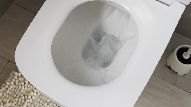 White toilet bowl in a bathroom. Closeup. Flush water away