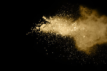 Golden powder explosion on black background. Freeze motion.