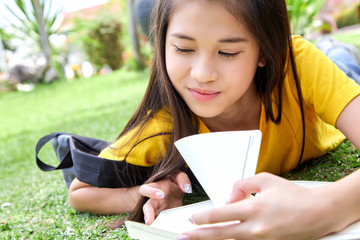 female teenager smiling while lying on grass field