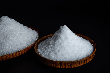 Coarse sea salt and fine salt on black background