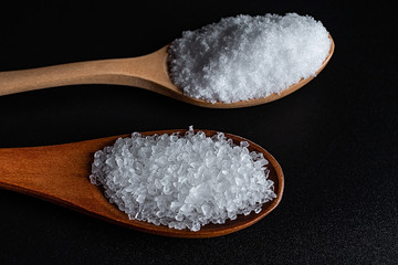 Coarse sea salt and fine salt on black background