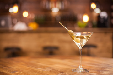 Single glass of dry martini in a restaurat over a wooden table