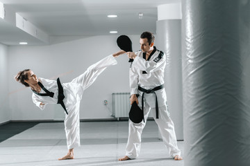 Caucasian handicapped highly motivated girl practicing taekwondo with her training. Girl kicking...