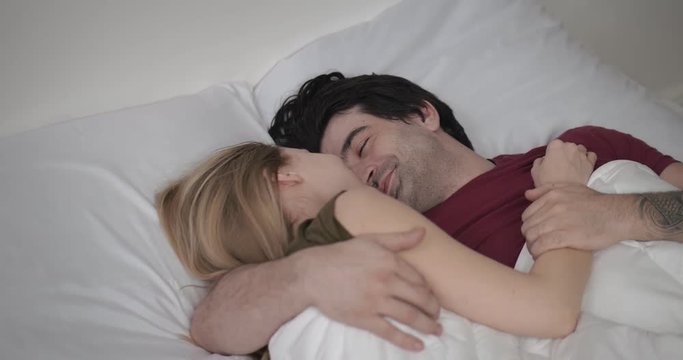 beautiful happy couple lying and hugging in bed at home