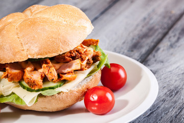 Fried chicken meat with cheese and vegetables in bun