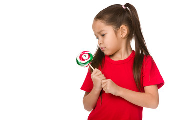 Beautiful upset little child girl with sweet candy lollipop isolated on white background