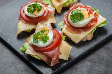 Delicious sandwich with prosciutto ham, cheese, tomato and egg