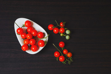 Small Tomato on black wood background.Food concept.