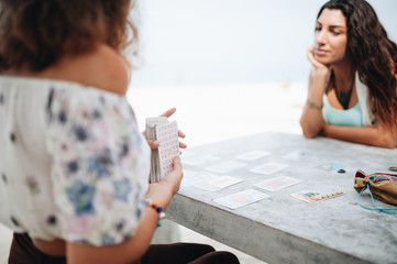 Woman is reading Tarot cards at the beach