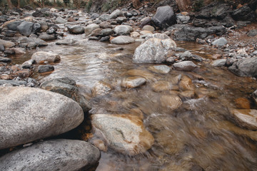 Mountain, transparent river, flowing among smooth stones. clous-up