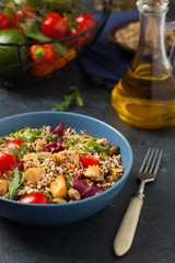 Salad with quinoa, avocado and chicken. Front view. Served in a blue bowl.