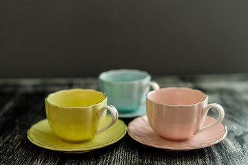 Colorful coffee cups blue, powdery and yellow on a wooden background
