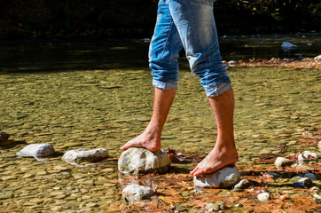 passing the river on the stonen young man feet river voidomatis zagoria ioannina  greece
