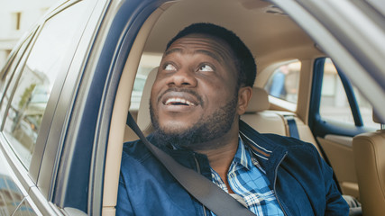 Traveling Young Man Rides on a Passenger Seat of a Car, Opens Window and Looks on a Big City in Wonder.