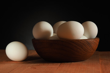 Chicken eggs in a wooden bowl on a wooden surface. Easter
