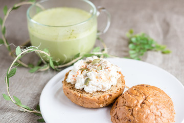 Sandwich with cottage cheese and pumpkin seeds with matcha tea on a rustic napkin
