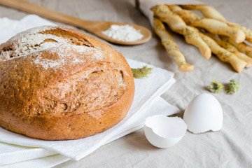 rye bread or sliced bread on white napkin with spike of wheat, eggshell and flour