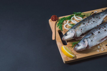 Grey mullet fish on the wooden board wıth lemon, onion and spices.