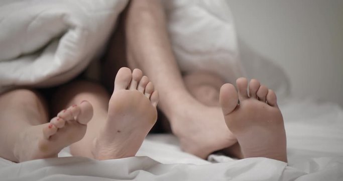 Close up of four feet of couple in a bed - Image