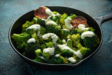 Fried broccoli with garlic yogurt and lemon zest in cast iron skillet, frying pan