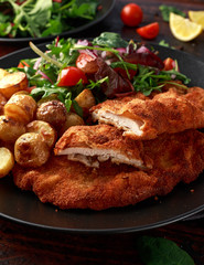 Homemade breaded pork schnitzel with roast potato and vegetables