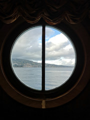 Fototapeta na wymiar A view from the porthole window of a cruise ship, showing the city of Messina, Italy.