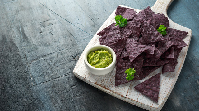 Blue corn Organic tortilla chips with Guacamole on white wooden board